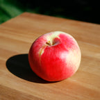 A large red Monty's Surprise apple on a wooden surface