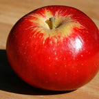 Red Akane apple on a wooden surface